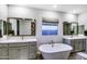 Elegant bathroom with double sinks, a soaking tub, and a large mirror at 17316 W Seldon Ln, Waddell, AZ 85355