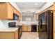 Well-equipped kitchen, featuring wood cabinets and black appliances at 18650 N 91St Ave # 1401, Peoria, AZ 85382