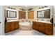 Large bathroom with dual vanities, a soaking tub, and wood cabinets at 5701 N 105Th Ln, Glendale, AZ 85307