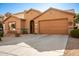 Front view of a tan house with a two-car garage and driveway at 45759 W Morning View Ln, Maricopa, AZ 85139