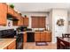 Modern kitchen with wood cabinets, black appliances, and tile flooring at 45759 W Morning View Ln, Maricopa, AZ 85139