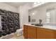 Clean bathroom, granite countertop, dark wood cabinets, and a shower with a black and white patterned curtain at 6523 N 135Th Dr, Glendale, AZ 85307