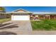 House exterior featuring a white garage door, well-manicured lawn, and a brick walkway at 10728 W Cheryl Dr, Sun City, AZ 85351