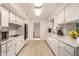 Long galley kitchen boasts white cabinets and tile flooring at 10728 W Cheryl Dr, Sun City, AZ 85351