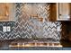 Kitchen backsplash with a modern herringbone pattern in gray and copper tones at 2009 S Raindance Rd, Apache Junction, AZ 85119