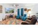 Cozy living room with teal armchairs, a brown sofa, and a large TV at 45467 W Dirk St, Maricopa, AZ 85139