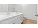 Modern bathroom with double vanity, white cabinets, and wood-look tile floor at 3787 S 233Rd Ln, Buckeye, AZ 85326