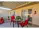 Covered patio with red chairs, table, and small potted plants at 10412 W Audrey Dr, Sun City, AZ 85351