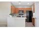 Kitchen with wood cabinets, black appliances, and a breakfast bar at 12391 W Tonto St, Avondale, AZ 85323