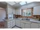 Bright kitchen featuring white cabinets, double sink, and brick accent wall at 10610 W Saratoga Cir, Sun City, AZ 85351