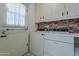 Laundry room with washer, dryer, and brick accent wall at 10610 W Saratoga Cir, Sun City, AZ 85351
