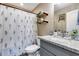 Clean bathroom with granite countertop, floral shower curtain and wood shelves at 10638 N 15Th Ln, Phoenix, AZ 85029