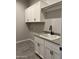 Laundry room with white cabinets, sink, and gray tile floors at 16068 W Questa Dr, Surprise, AZ 85387