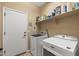 Bright laundry room with washer, dryer, and storage shelves at 22958 W Devin Dr, Buckeye, AZ 85326