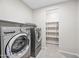 Bright laundry room, complete with washer, dryer, and shelving for storage at 26001 W Matthew Dr, Buckeye, AZ 85396