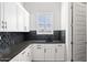 Well-appointed laundry room with white cabinets, dark countertop and a window at 8565 E Arroyo Seco Rd, Scottsdale, AZ 85266