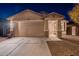 Tan house with a two-car garage and stone accents at night at 11828 W Donald Dr, Sun City, AZ 85373