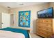Bedroom with wooden dresser and large TV at 16938 W Desert Rose Ln, Surprise, AZ 85387