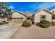 Tan house with a two-car garage, landscaping, and a gravel driveway at 18348 W Hatcher Rd, Waddell, AZ 85355