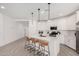 Modern white kitchen with island and breakfast bar, featuring contemporary lighting and appliances at 9316 S 39Th Dr, Laveen, AZ 85339