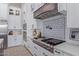 Modern kitchen features a gas cooktop, custom range hood, and white cabinetry at 21121 E Marsh Rd, Queen Creek, AZ 85142