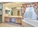 Elegant bathroom with double sinks, a large bathtub and updated light fixtures at 11857 N 81St St, Scottsdale, AZ 85260