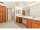 Bathroom with shower, double vanity, and wood cabinets at 14543 W Bison Path, Surprise, AZ 85374