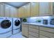 Laundry room with washer, dryer, and ample cabinet space at 11696 E Charter Oak Dr, Scottsdale, AZ 85259