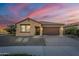 Tan one-story house with brown roof, two car garage, and landscaping at sunset at 20871 E Kingbird Dr, Queen Creek, AZ 85142