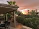 Patio with table and chairs, covered pergola, and desert landscaping with sunset view at 3146 N 157Th Ln, Goodyear, AZ 85395