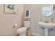 Powder room with a pedestal sink, toilet, and decorative mirror at 3931 N Golf Dr, Buckeye, AZ 85396