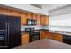 Modern kitchen with black appliances and wood cabinets at 44852 W Sage Brush Dr, Maricopa, AZ 85139