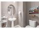 Small powder room with pedestal sink, toilet, and glass shelf at 27437 W Yukon Dr, Buckeye, AZ 85396