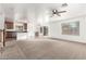 Open-concept living area featuring carpeted flooring and ceiling fan, adjacent to the kitchen at 21869 W Mohave St, Buckeye, AZ 85326