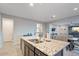 Granite kitchen island with double sink and view into adjacent living space at 22918 E Marsh Rd, Queen Creek, AZ 85142