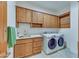 Bright laundry room with modern washer, dryer, and wood cabinets at 12832 E Sorrel Ln, Scottsdale, AZ 85259