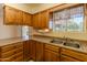 Well-lit kitchen featuring wood cabinets and double sink at 10103 W Forrester Dr, Sun City, AZ 85351