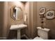 Elegant powder room with pedestal sink, decorative mirror, and toilet at 24686 N 120Th Pl, Scottsdale, AZ 85255