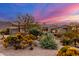 Desert landscaping surrounds this single-story home with a three-car garage at sunset at 11557 E Four Peaks Rd, Scottsdale, AZ 85262