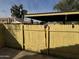 Yellow wooden fence encloses a patio area with a carport at 4766 W Rose Ln, Glendale, AZ 85301