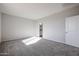 Well-lit bedroom featuring neutral carpeting and access to bathroom at 35595 W Mallorca Ave, Maricopa, AZ 85138