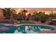 Sunset view of kidney-shaped pool and spa with landscaping at 18228 N San Salvador Ct, Surprise, AZ 85374