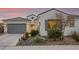 Single-story home with gray garage doors, landscaping, and desert plants at 16573 W Valencia Dr, Goodyear, AZ 85338