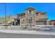 Two-story house with tan exterior, three-car garage, and desert landscaping at 8680 W Quail Track Dr, Peoria, AZ 85383