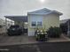 Yellow single wide home with carport and golf cart at 8700 E University Dr # 545, Mesa, AZ 85207