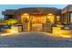 Desert home entrance with stone pillars and ornate gate at dusk at 15405 E Cavedale Dr, Scottsdale, AZ 85262