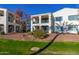 Back exterior view, two-story stucco home with grassy area and desert landscaping at 14200 W Village Pkwy # 106, Litchfield Park, AZ 85340