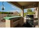 Covered patio with a built-in grill, a tiled countertop, and desert landscaping at 684 S 231St Dr, Buckeye, AZ 85326