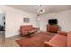 Living room with two orange couches, wood floors, and a TV at 2325 W Orchid Ln, Phoenix, AZ 85021