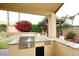 Outdoor kitchen area on the covered patio with a built-in grill, pergola, and lush backyard views at 5812 E Grandview Rd, Scottsdale, AZ 85254